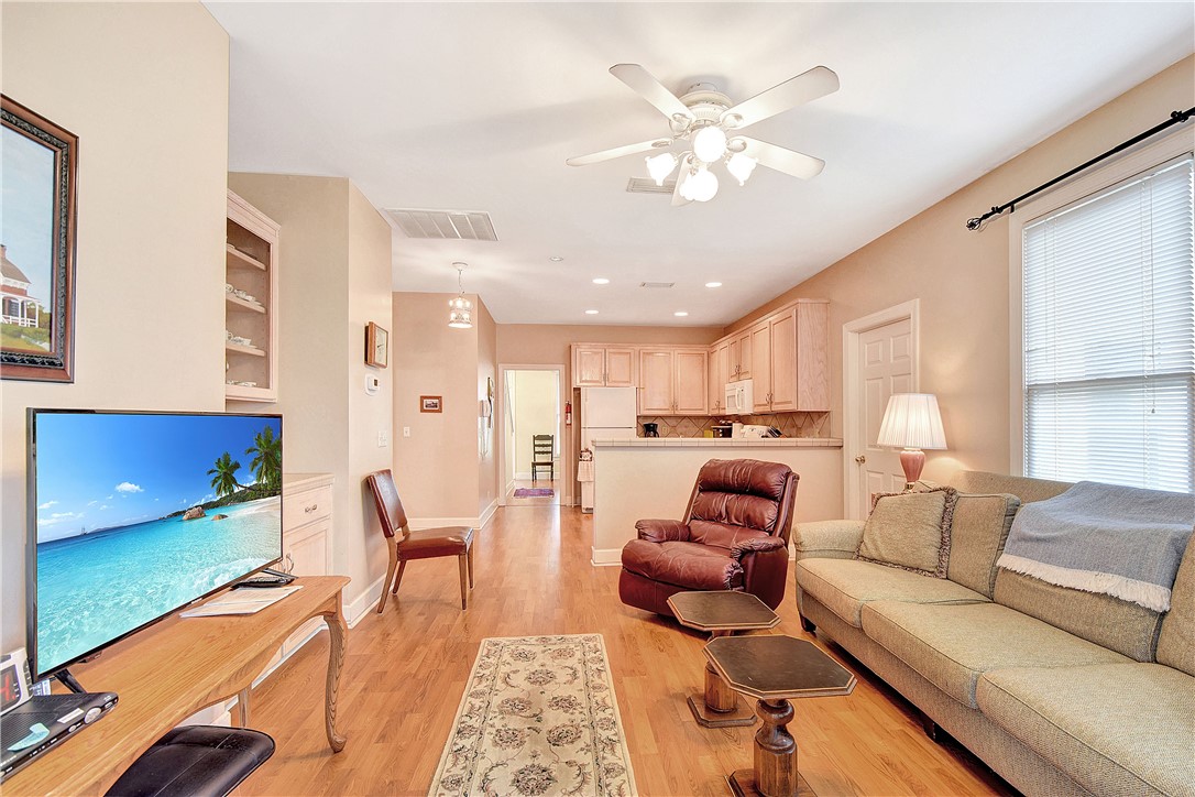 Living room with a beige sofa and leather recliner opening into a compact kitchen.