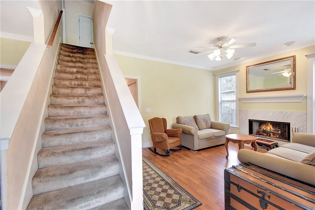 Living room with a carpeted staircase, hardwood floors, and a lit fireplace.