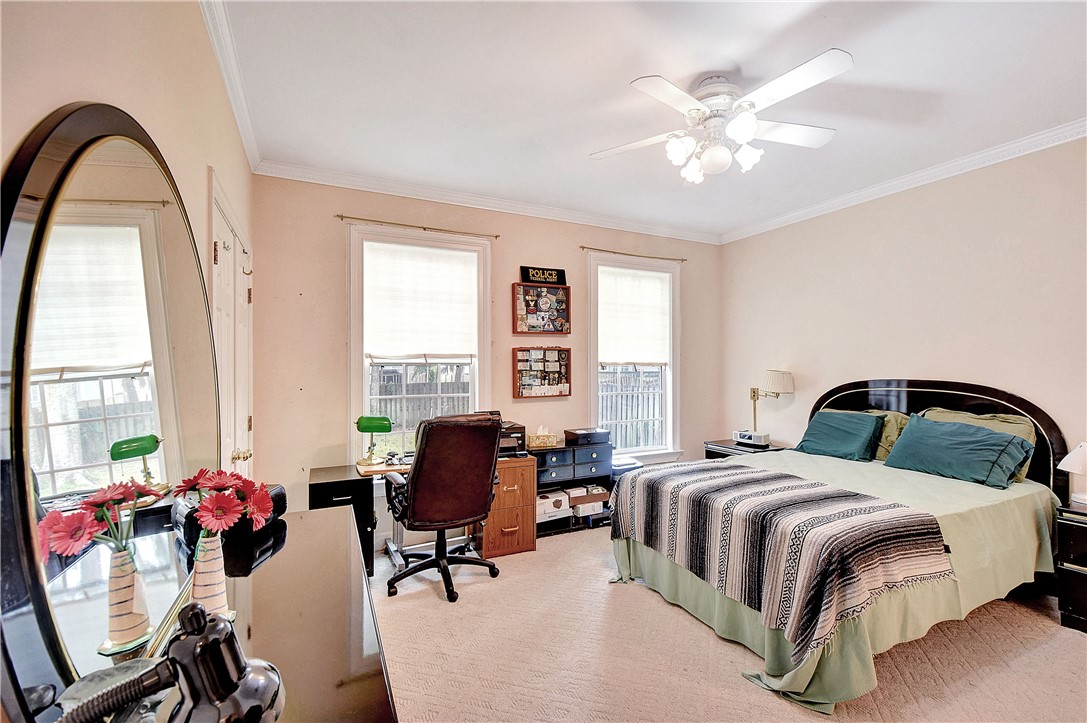 Bedroom with a large bed, desk, and arched full-length mirror beside two windows.