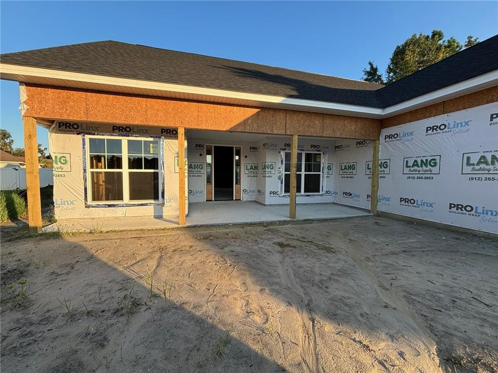 House under construction with exposed sheathing, an unfinished covered porch, and a bare dirt yard.