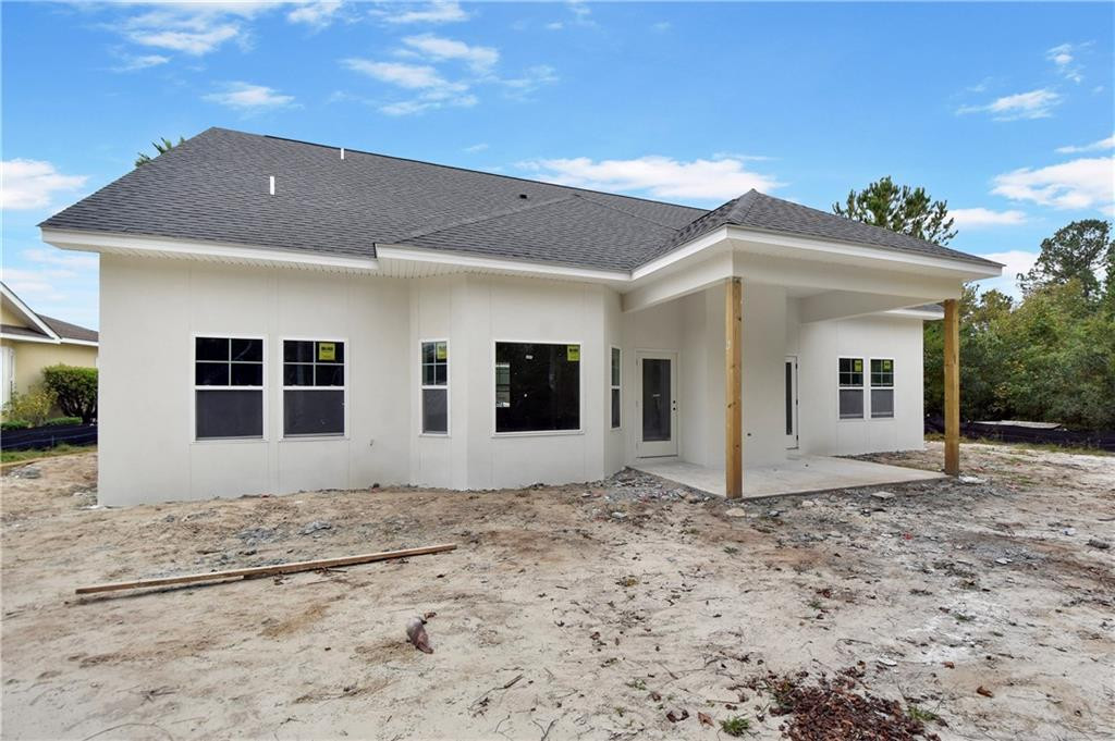 White single-story home under construction with a dark roof and covered porch.