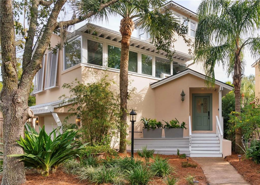 Two-story peach home with a green front door, white porch steps, and palm trees.