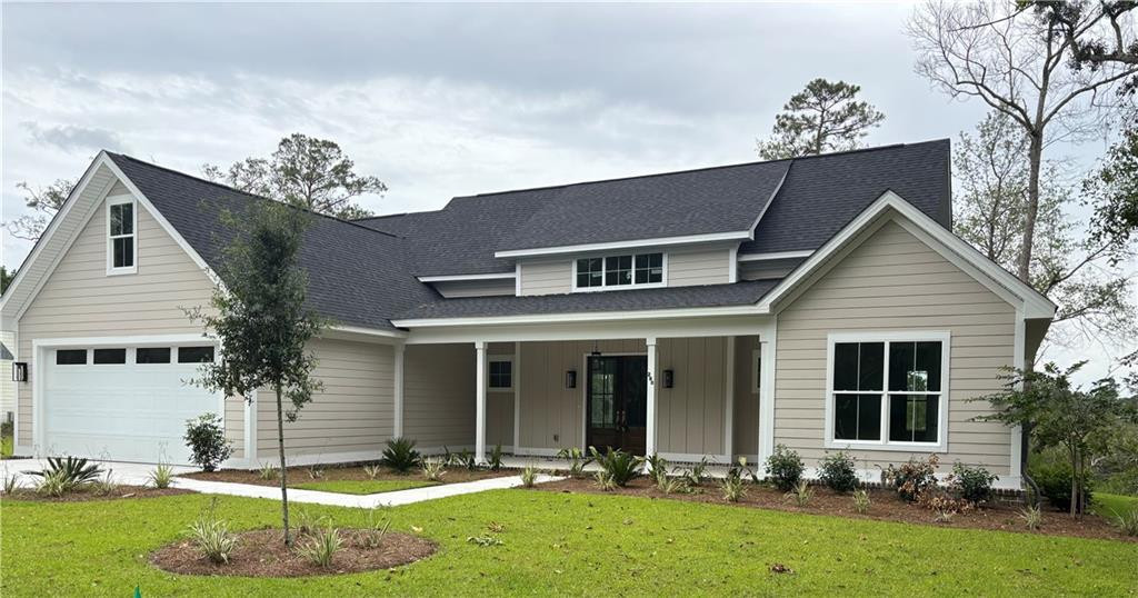 Beige-sided home with dark gabled roofs, a double garage, and covered front entry.