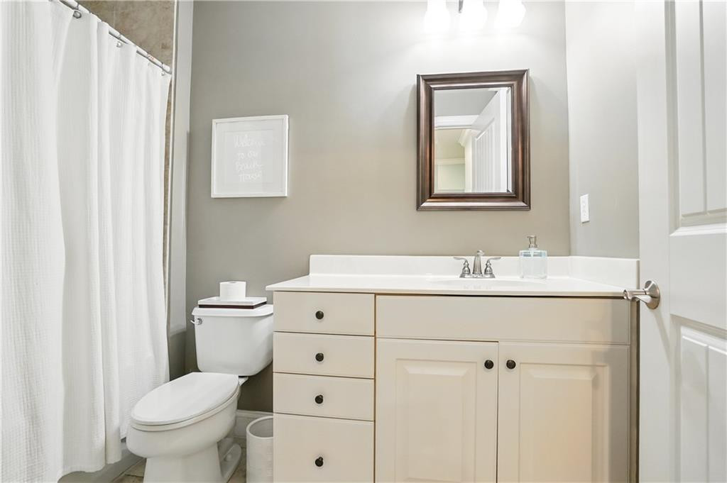 Bathroom with a white vanity, framed mirror, toilet, and shower curtain.