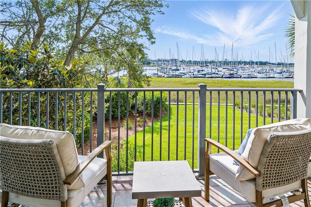 Waterfront patio with wicker seating overlooking a marina and sailboats.