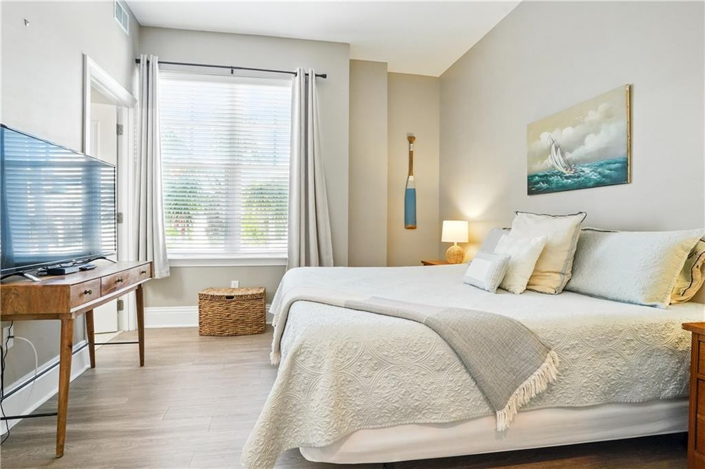 Bedroom with a white bed, bright window, television, and sailboat artwork.