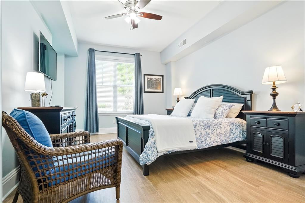 Bright bedroom with blue curtains, a dark wooden bed, and a wicker chair.