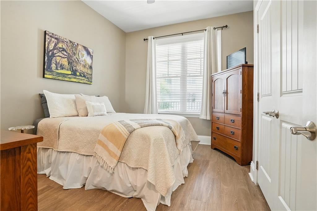 Bedroom with a white bed, wooden armoire, and a large curtained window.
