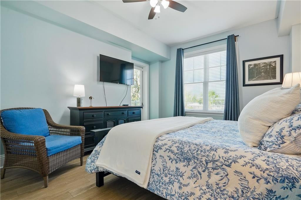 Bedroom with a blue-and-white floral bedspread, wicker chair, and window framed by blue curtains.