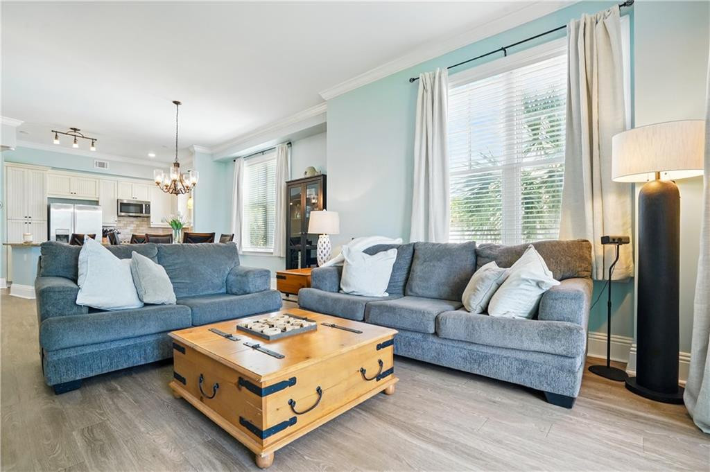 Living room with blue-gray sofas, a wooden trunk coffee table, and an open kitchen behind them.