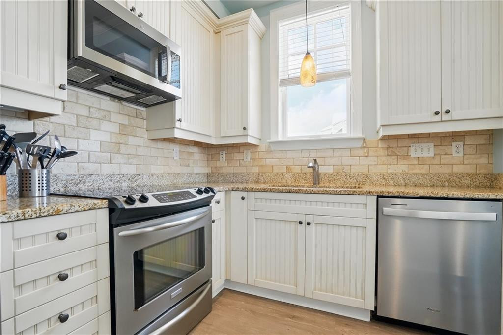 Kitchen with white beadboard cabinets, granite counters, and stainless steel appliances.