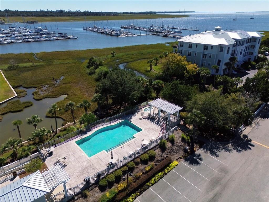 Waterfront condominium beside a marina, with a pool, marshland, and open water.