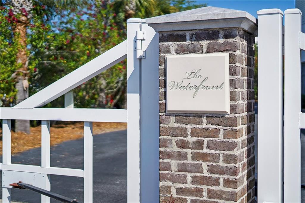 White entrance gate and brick pillar with a “The Waterfront” sign.
