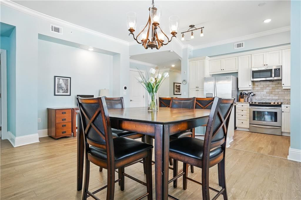 Dining area with a dark wood table and chandelier beside a white kitchen.