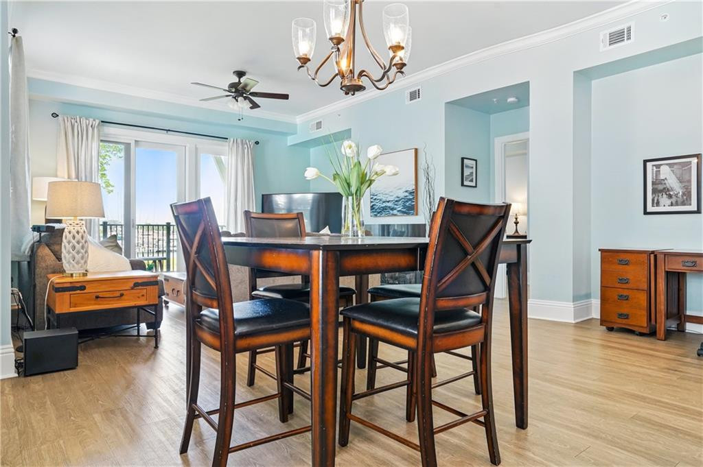 Dining area with a dark wood table, chandelier, and sliding glass doors to a balcony.