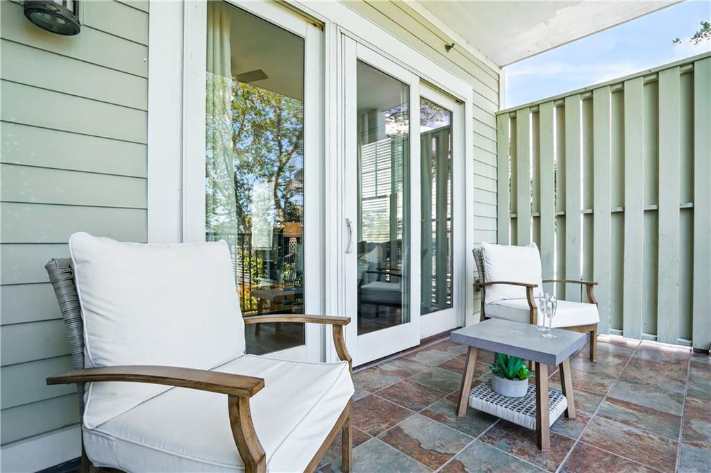 Covered patio with white-cushioned chairs, a small table, and sliding glass doors.
