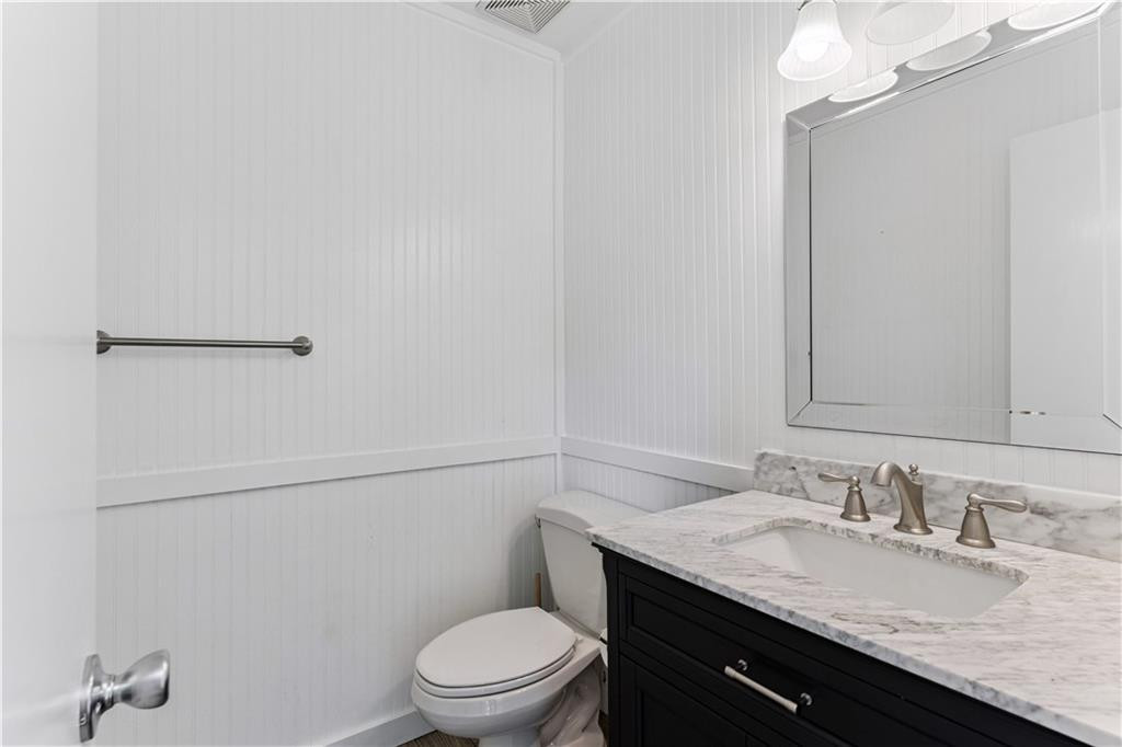 Bathroom with a black marble-topped vanity, integrated sink, and white paneled walls.