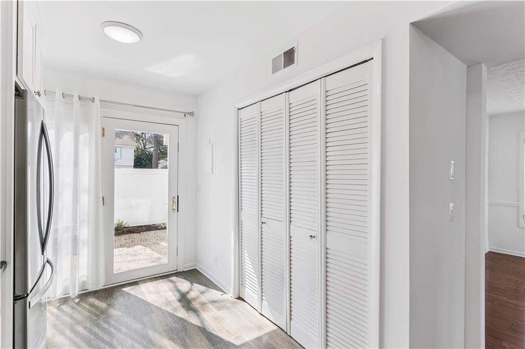Bright kitchen with a stainless steel refrigerator, louvered doors, and a glass door to the patio.