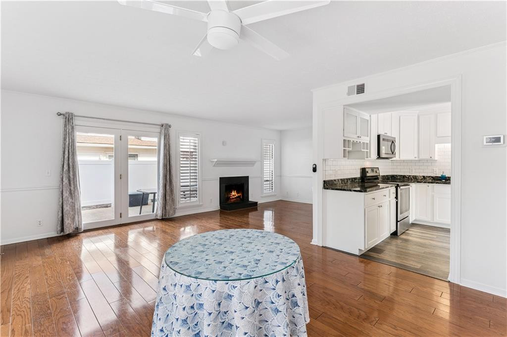 Living room with hardwood floors, a fireplace, French doors, and an open white kitchen.