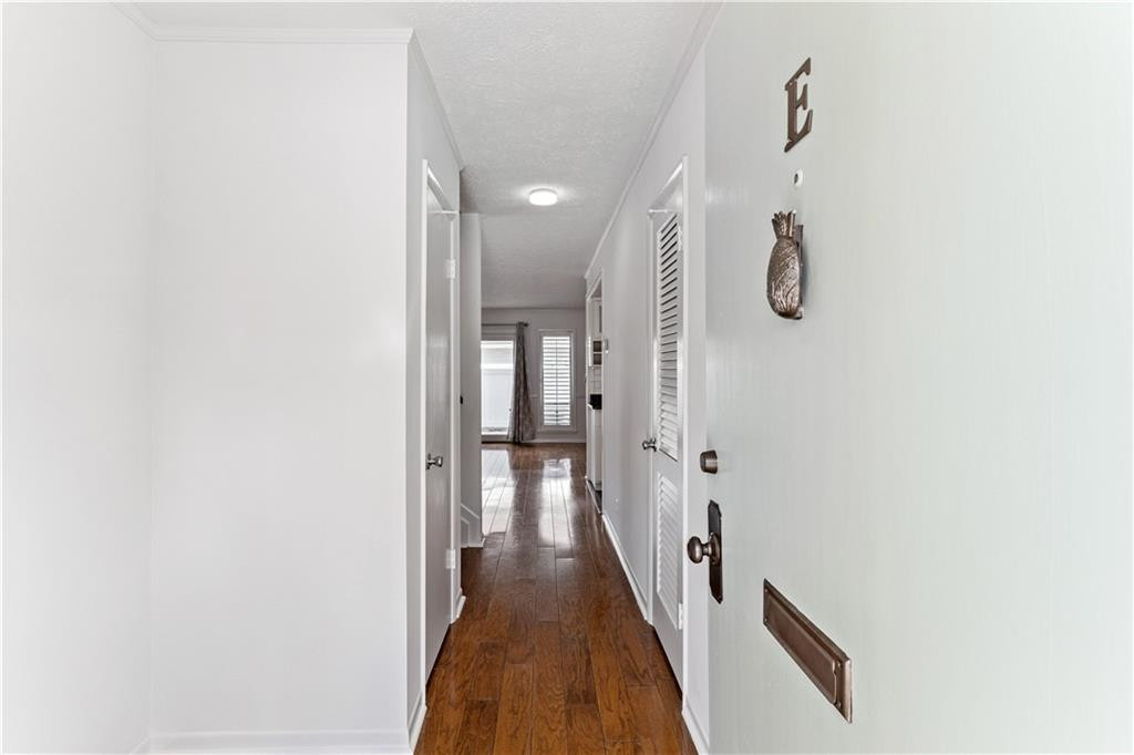 Entry hallway with hardwood floors, white walls, and louvered doors.
