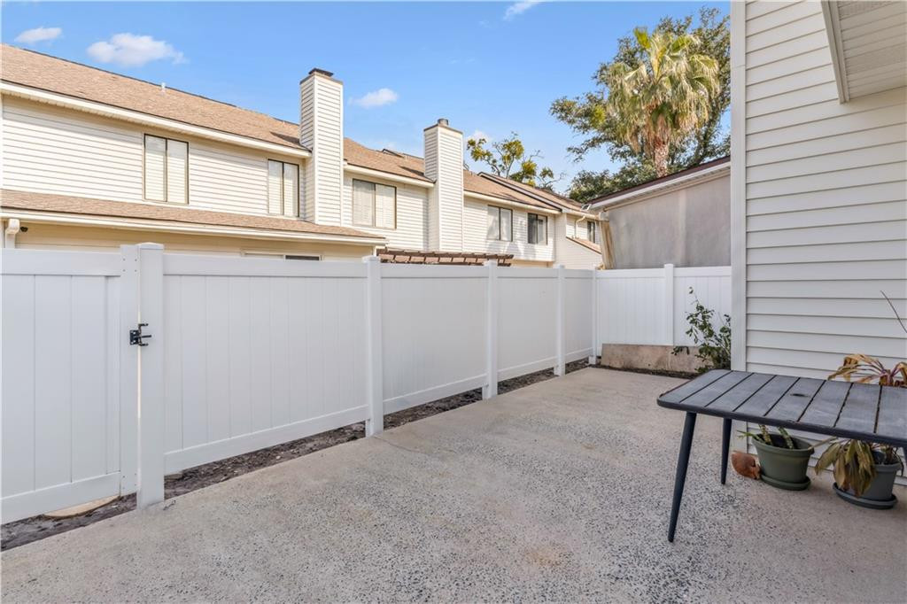 Concrete patio with white privacy fencing, a small table, and potted plants.