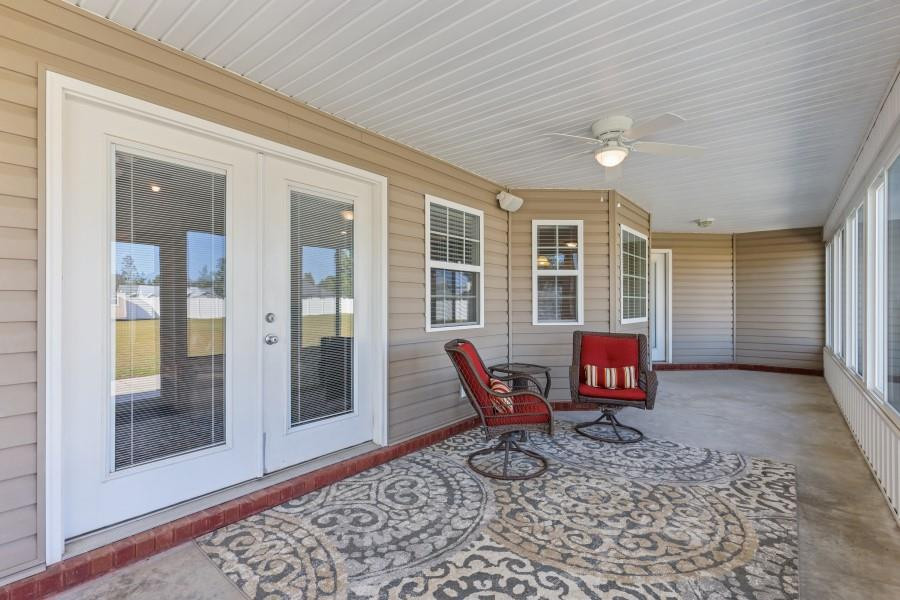 Enclosed porch with two red chairs, a patterned rug, and large windows.