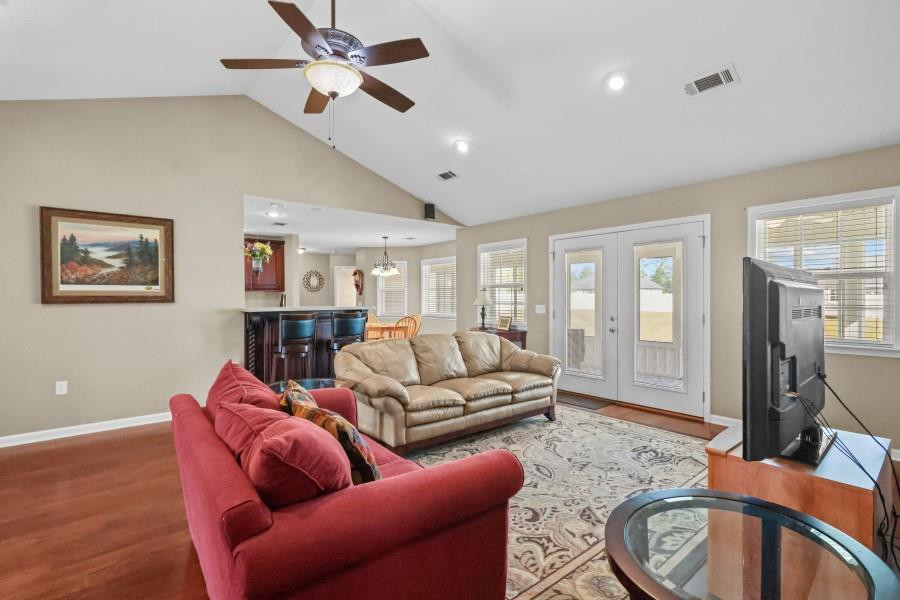 Living room with vaulted ceiling, red and beige sofas, and French doors.
