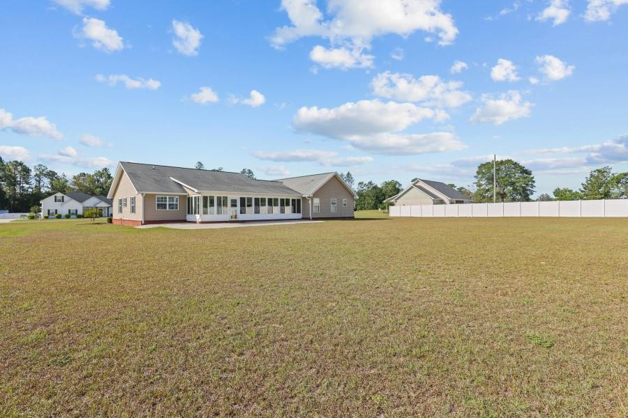 Single-story home with a long row of rear windows overlooking a broad open lawn.