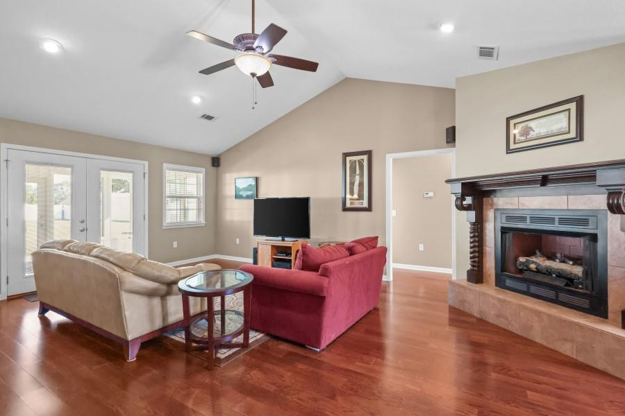 Living room with vaulted ceiling, red sofa, glass doors, and a fireplace.