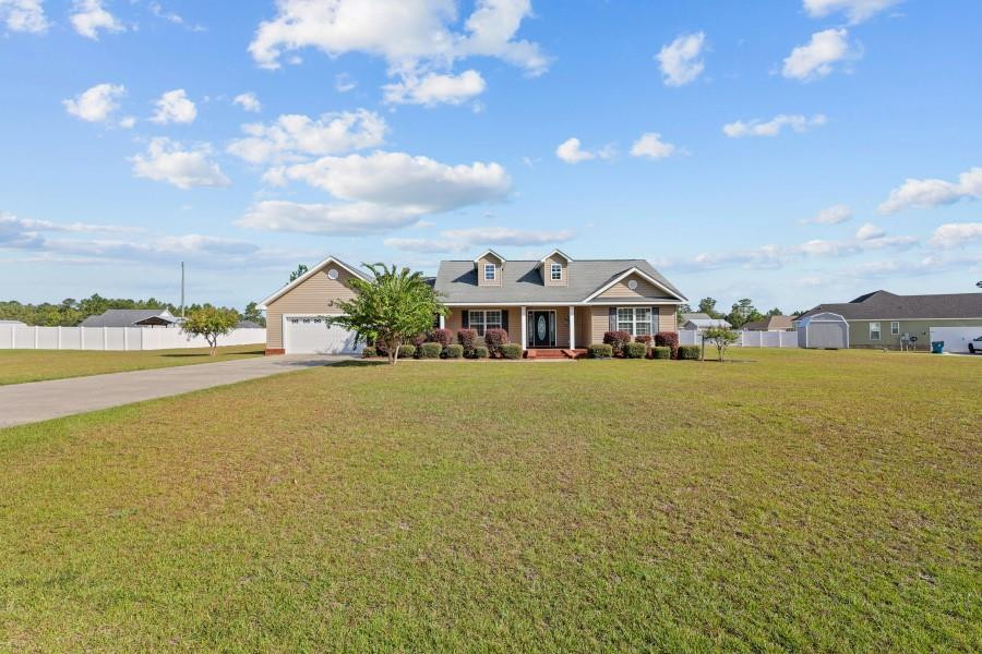 Single-story home with two dormers and an attached garage, set behind a broad lawn.