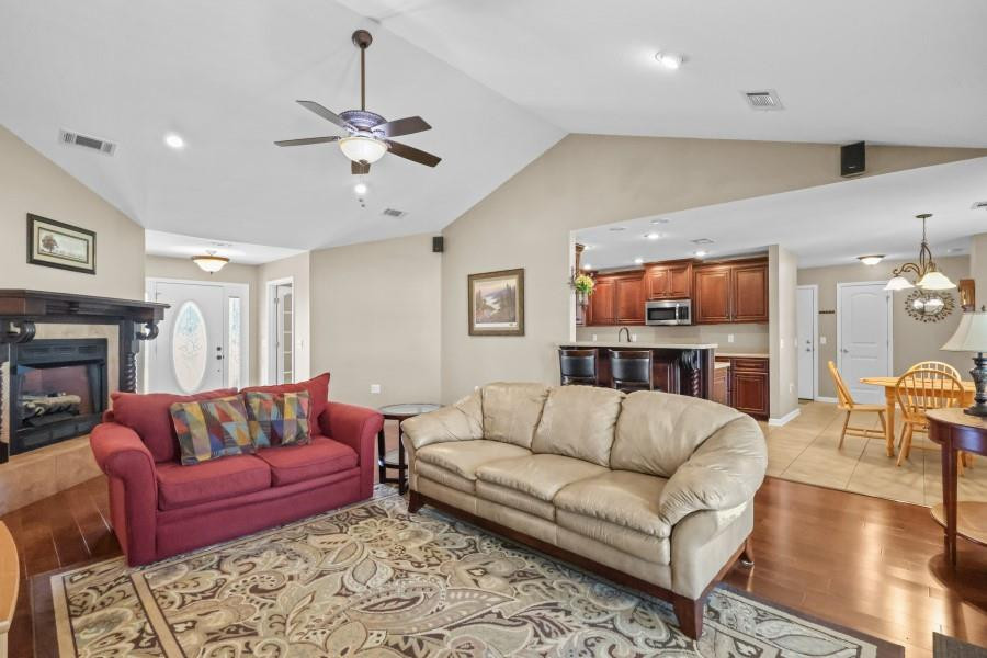 Living room with a fireplace, red loveseat, beige sofa, and open view into the kitchen.