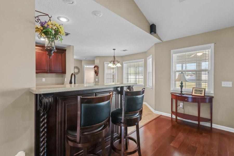 Kitchen breakfast bar with a light stone counter, two upholstered stools, and hardwood floors.
