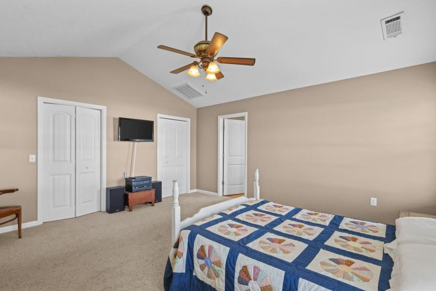 Bedroom with a blue-and-white patchwork quilt, ceiling fan, and wall-mounted television.