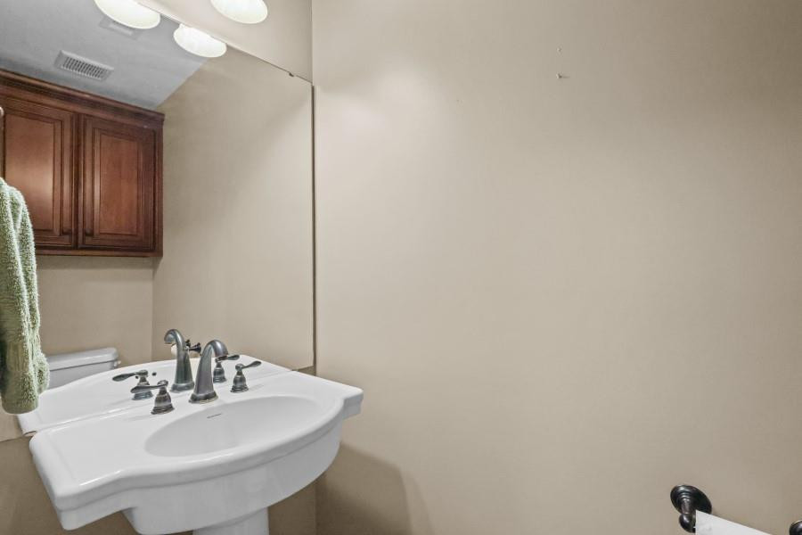 Bathroom vanity with a white sink, chrome faucets, large mirror, and dark wood cabinet.