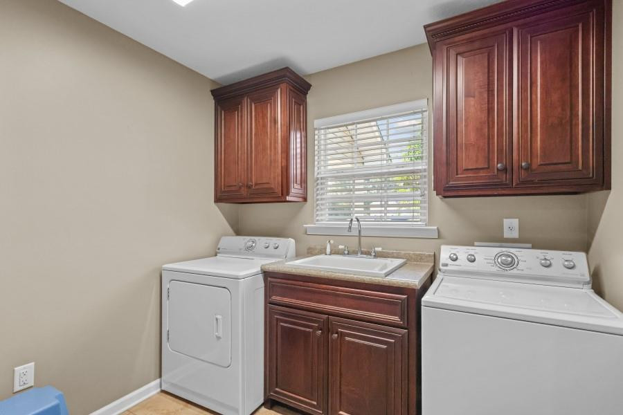 Laundry room with a washer and dryer, utility sink, and dark wood cabinets.