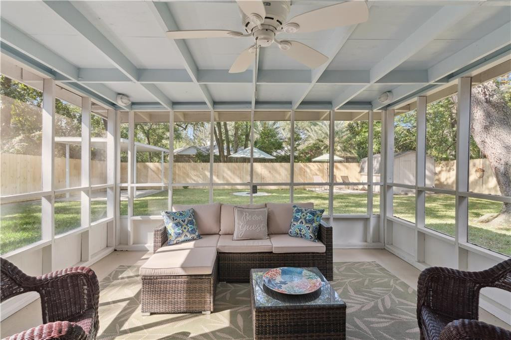 Screened porch with wicker seating, a ceiling fan, and views of the fenced backyard.