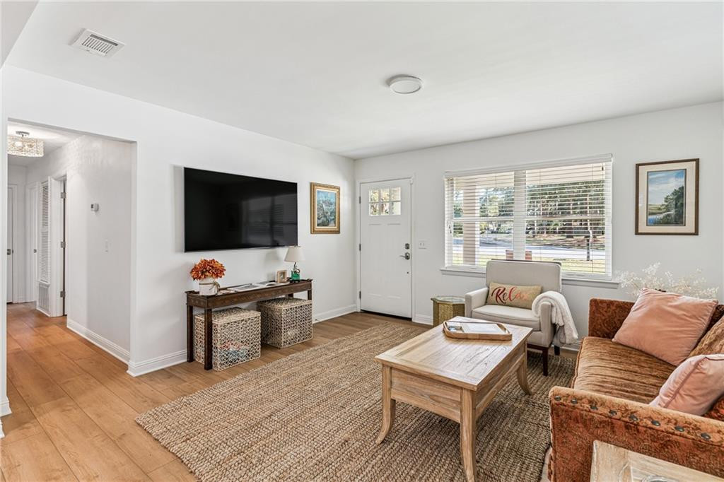 Living room with a woven rug, wooden coffee table, and rust-colored sofa beneath a wide window.