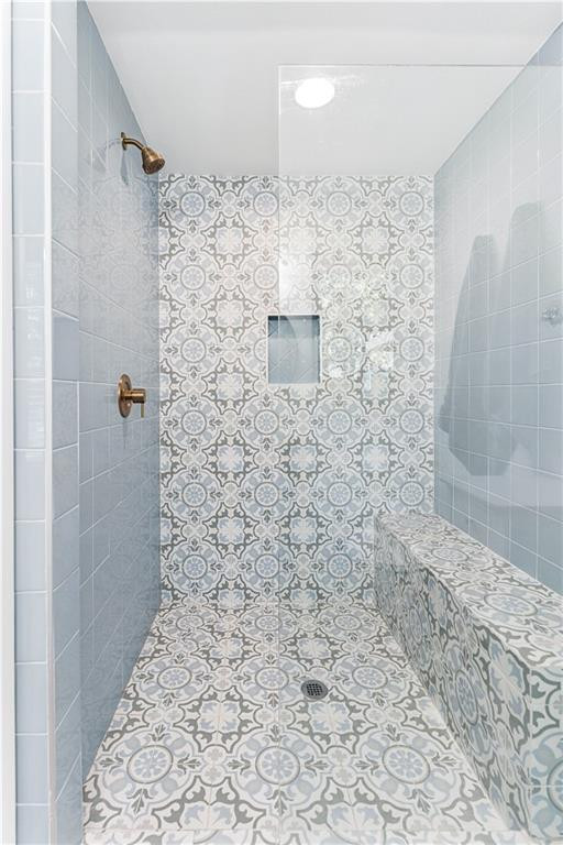 Walk-in shower with patterned tile, a built-in bench, recessed niche, and brass fixtures.