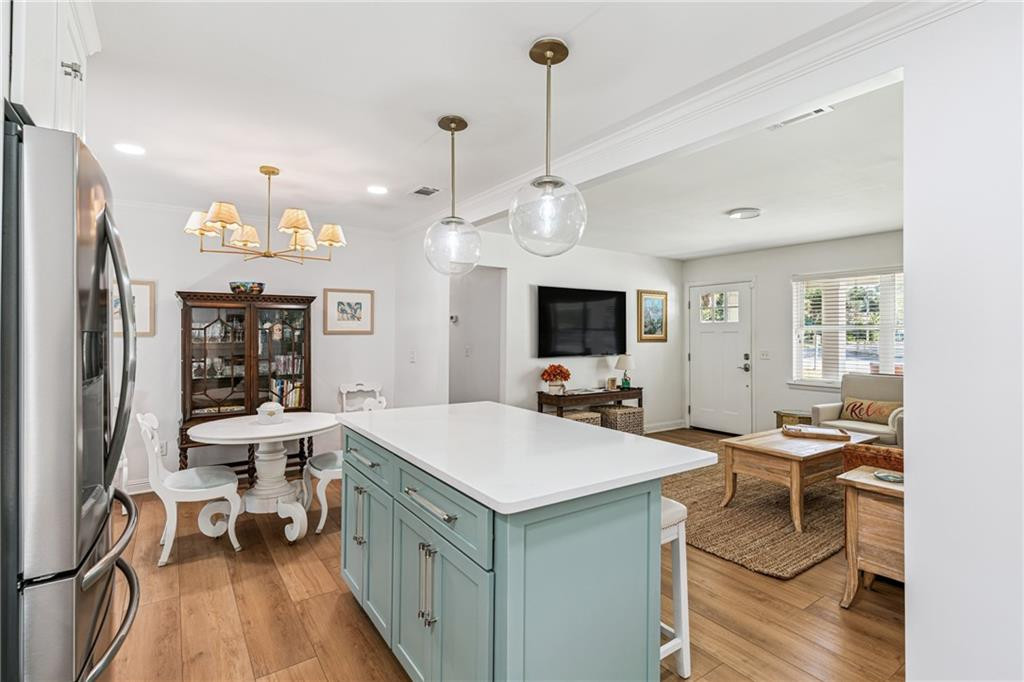 Open-plan kitchen with a pale blue island, dining nook, and adjoining living area.