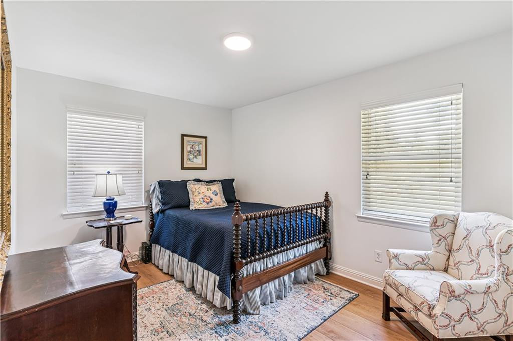 Bedroom with a dark wood bed, navy bedding, and a patterned armchair by the window.