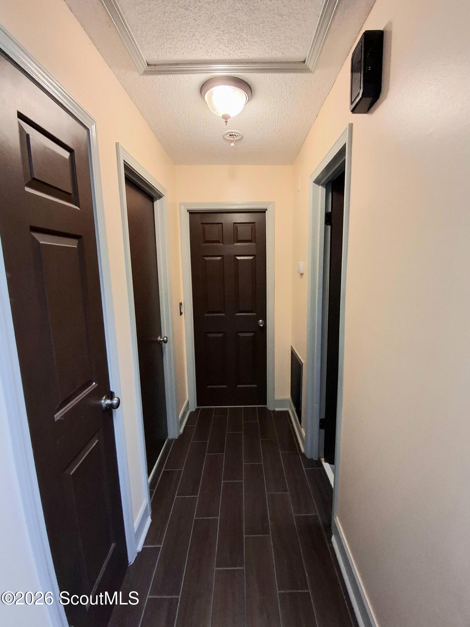 Hallway with dark paneled doors and dark tile flooring.