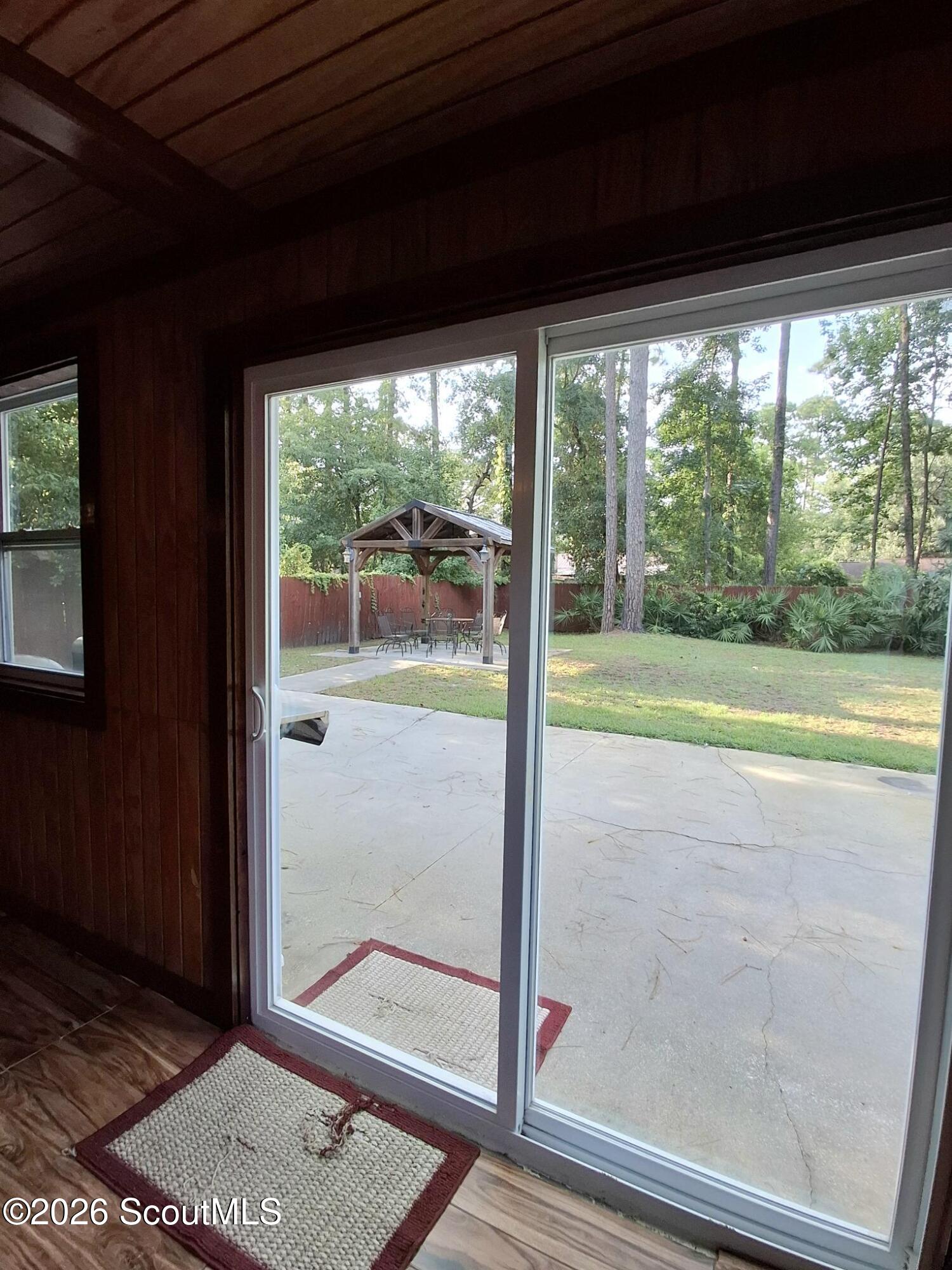 Sliding glass doors open onto a patio and fenced backyard with a wooden gazebo.