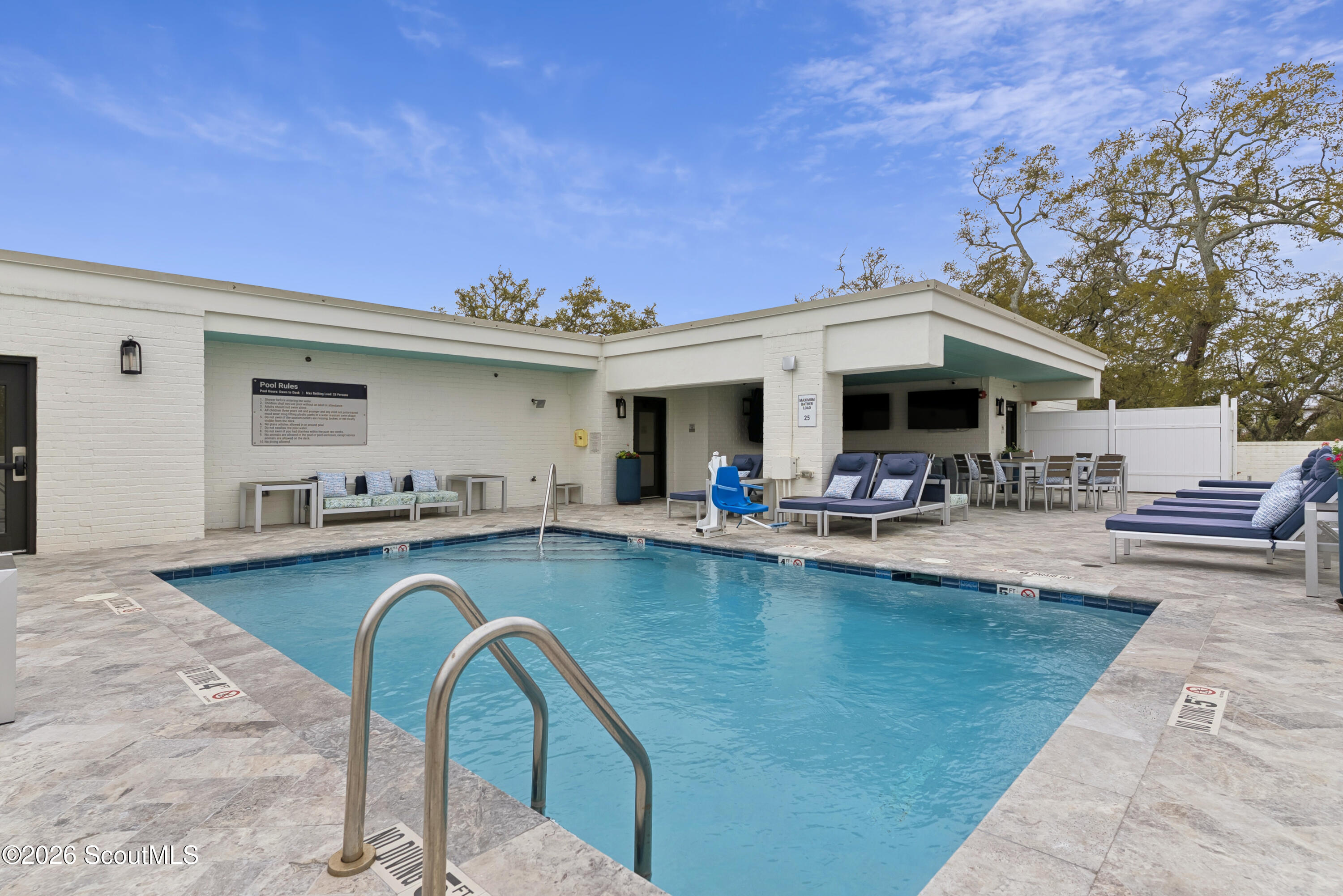 Outdoor pool with a stone deck, lounge chairs, and a covered poolside seating area.