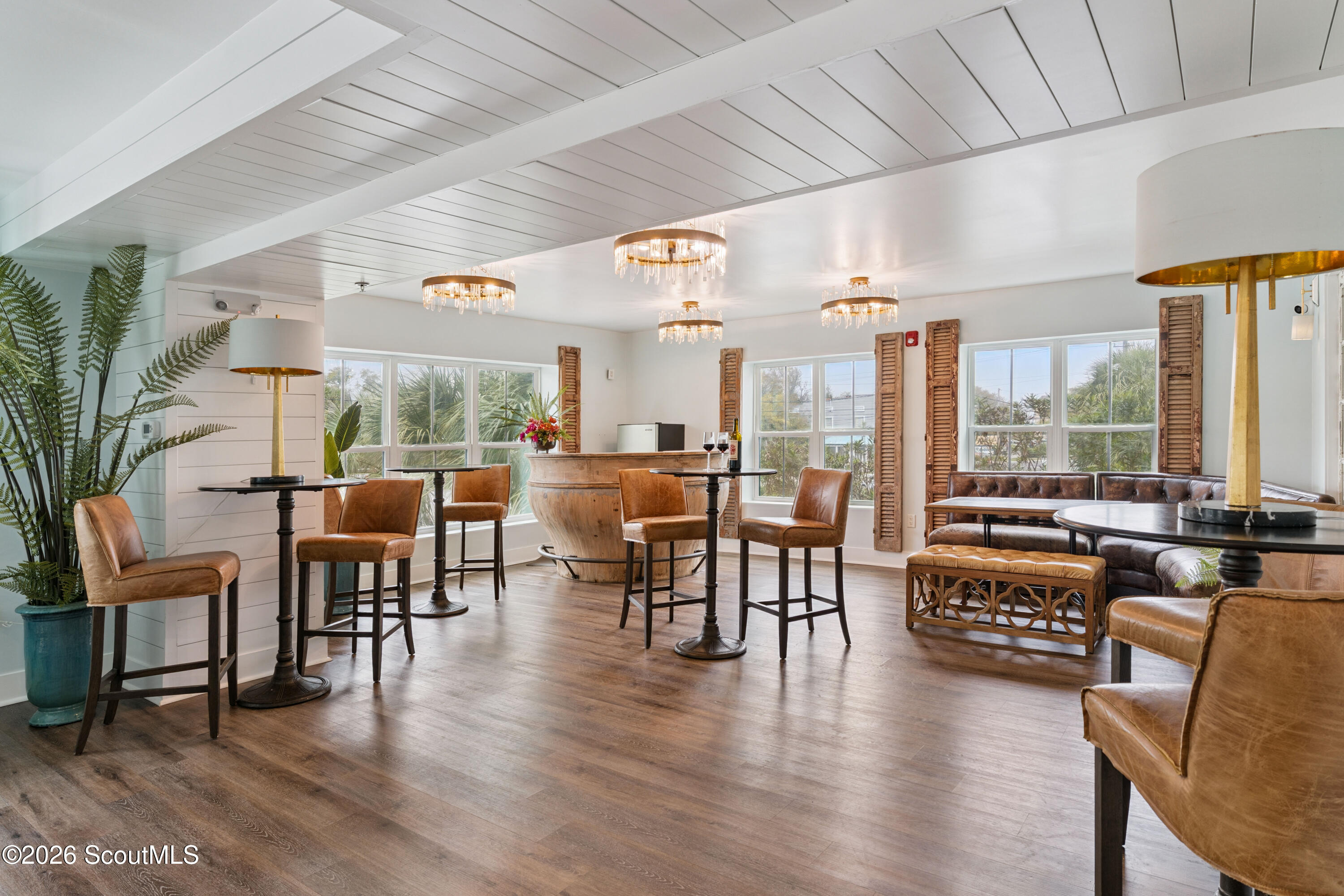 Furnished lounge with a curved wood bar, leather seating, and large windows.