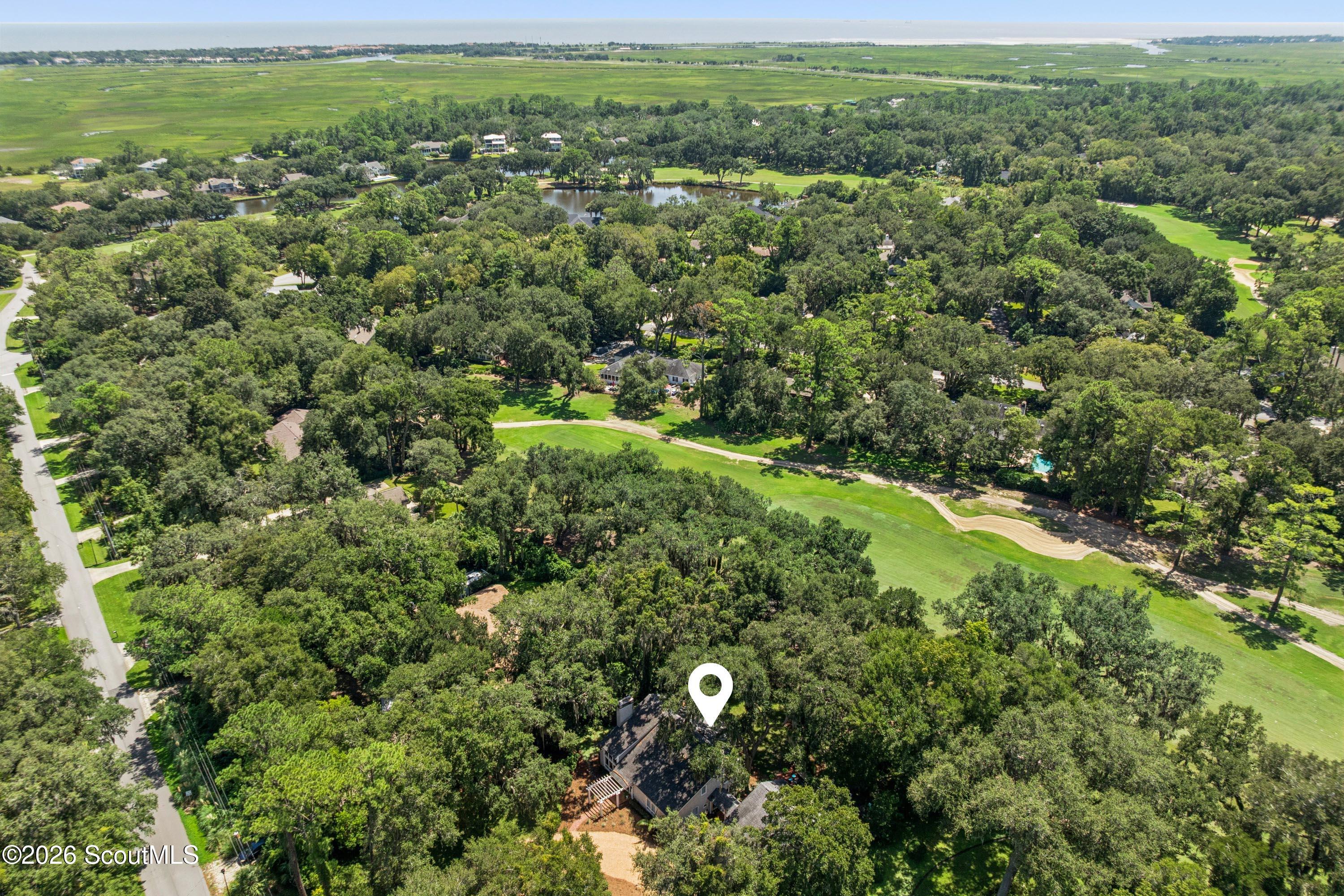 Aerial view of the home at 116 Palm Drive, surrounded by trees beside a golf course.