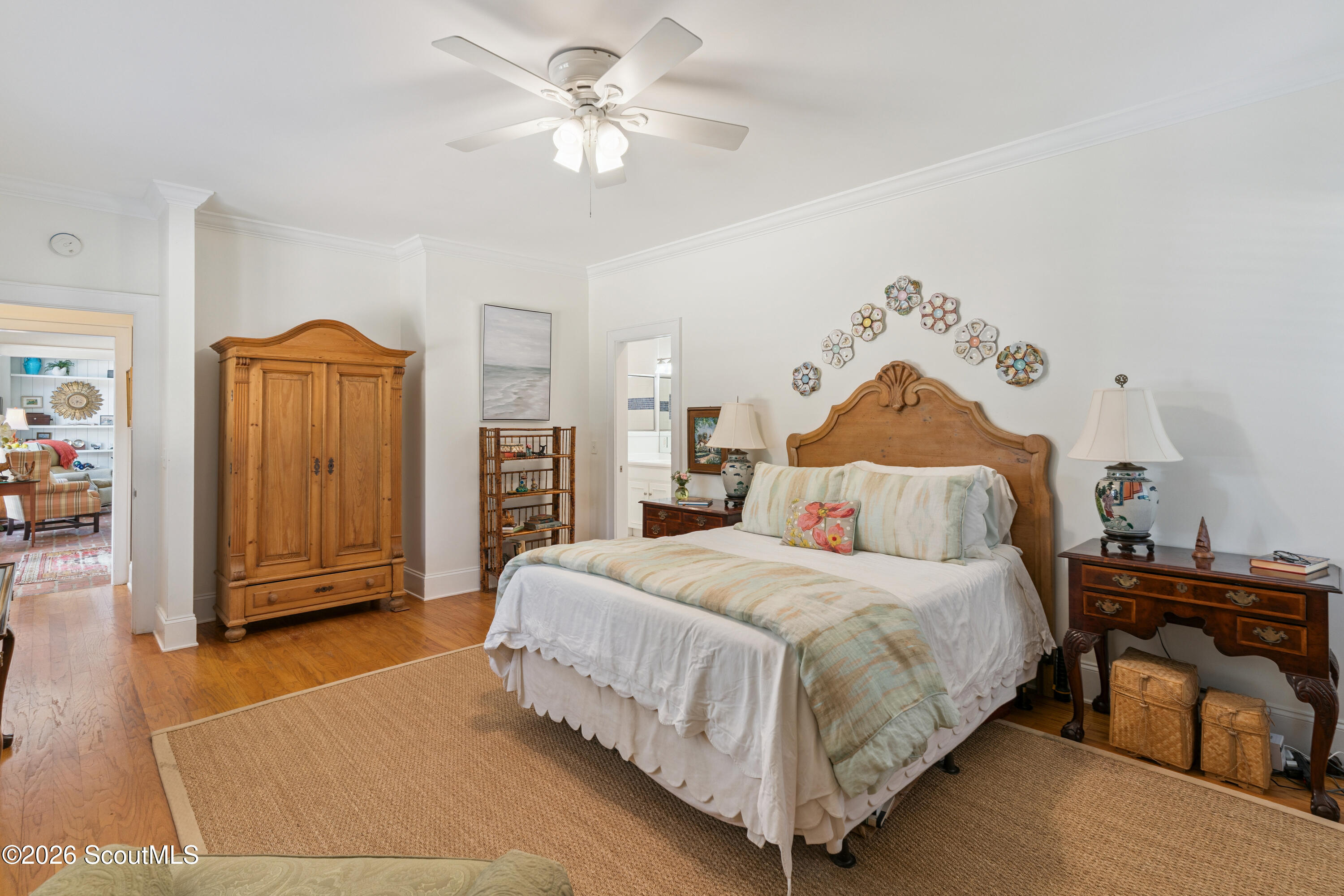 Furnished bedroom with a carved wooden bed, tall armoire, and colorful ceramic wall decorations.