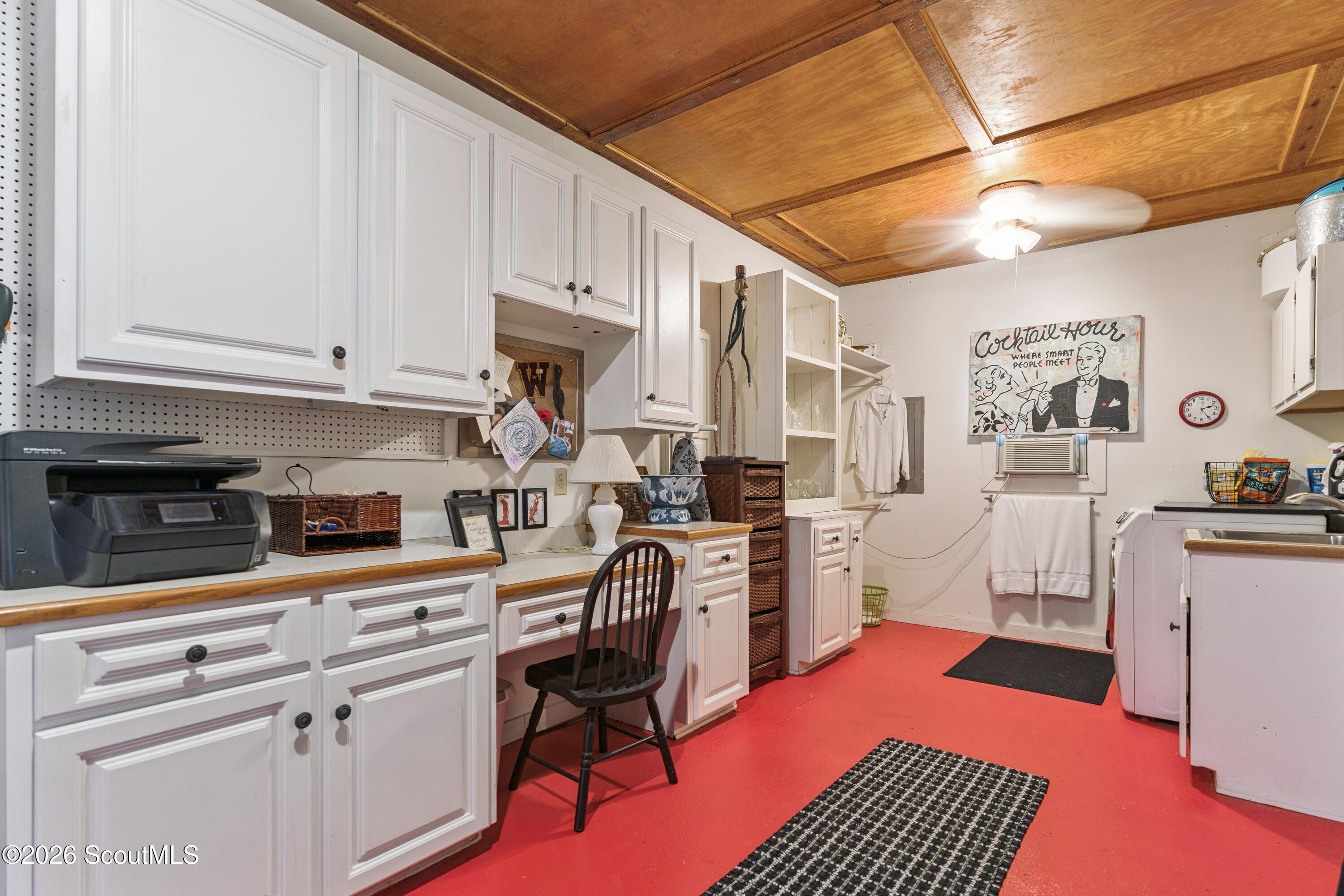 Laundry room with white cabinetry, red flooring, and a wood-paneled ceiling.