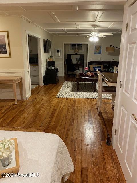 Living and dining area with polished hardwood floors, a ceiling fan, and a sofa.