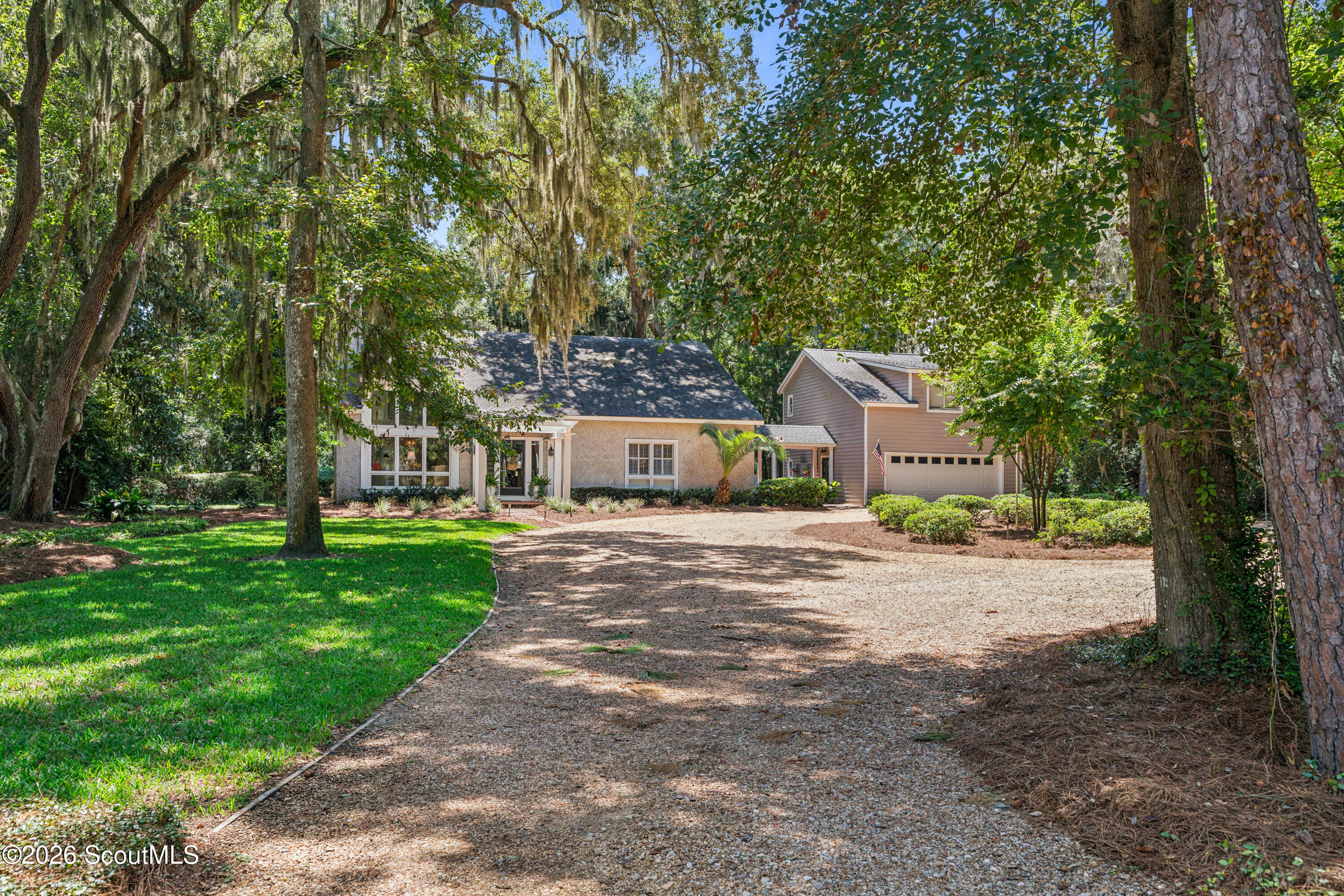 Home with attached garage and gravel driveway, framed by mature trees draped in Spanish moss.
