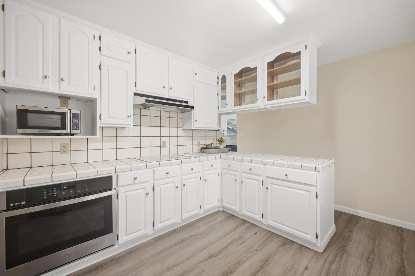 Kitchen with white cabinets, tiled counters, and stainless-steel appliances.